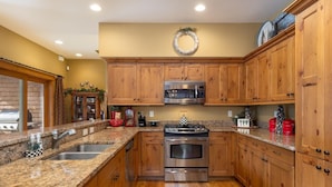 A kitchen with wooden cabinets, granite countertops, stainless steel appliances, and a decorative wreath on the wall. - 45 Thackwell Lane 4 Bedroom Townhouse by RedAwning (Keystone)