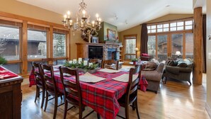 A dining area with a wooden table set for four, a fireplace, and a chandelier. - 45 Thackwell Lane 4 Bedroom Townhouse by RedAwning (Keystone)