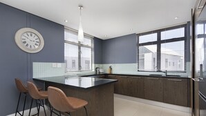 Une cuisine moderne avec un îlot central, des tabourets de bar et une horloge au mur.