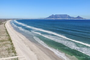A coastal beach with a clear view of the ocean, a sandy shoreline, and a distant mountain.