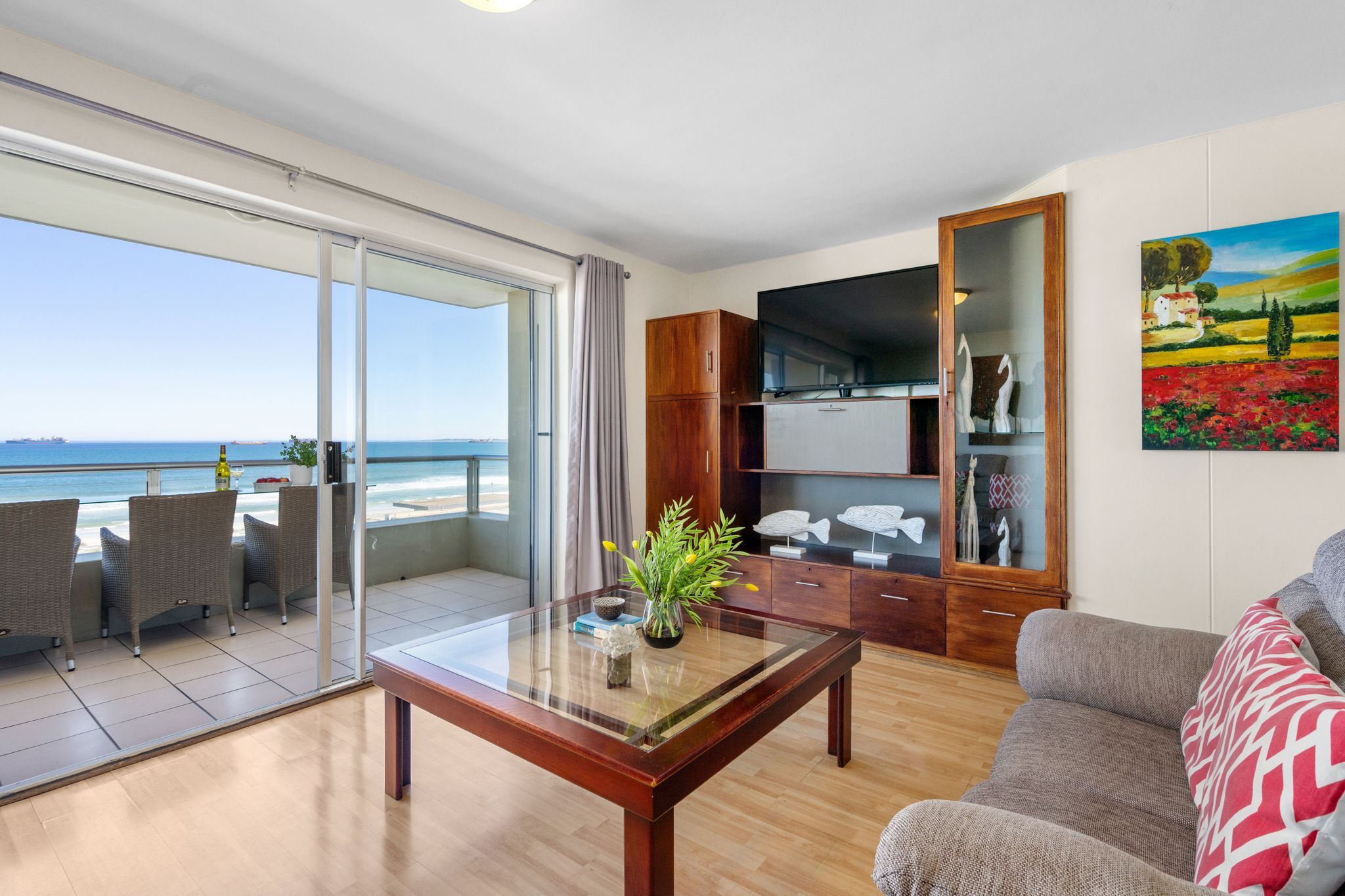 Un vaste espace de vie avec un balcon donnant sur la mer, une table basse en bois et un canapé.