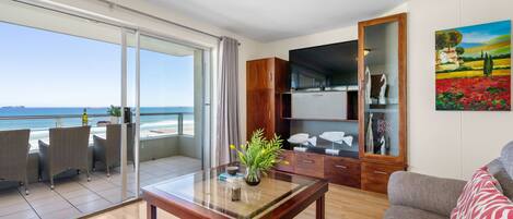 Un vaste espace de vie avec un balcon donnant sur la mer, une table basse en bois et un canapé.