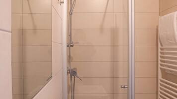 A modern bathroom with a glass-enclosed shower, a white sink, and a towel rack.
