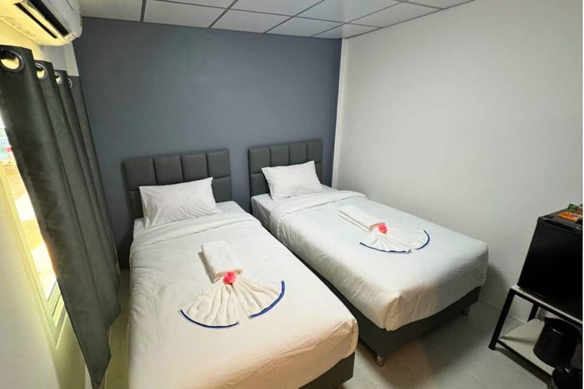 A hotel room with two single beds, a flat-screen TV, and a small kitchenette.