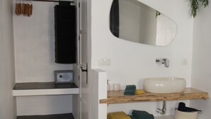 A bathroom with a white sink, mirror, and shelves. There is a towel rack with brown towels and a black towel. - Boutique B&B El Refugio (Alcaucin)