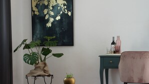 A room with a large plant, a small table with a vase, a desk with bottles, and a chair. - Boutique B&B El Refugio (Alcaucin)