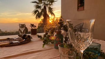 A table set with various glassware and a view of a sunset with palm trees.