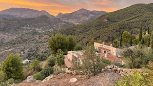 A rustic house with a red-tiled roof, surrounded by a mountainous landscape and dense greenery. - Boutique B&B El Refugio (Alcaucin)