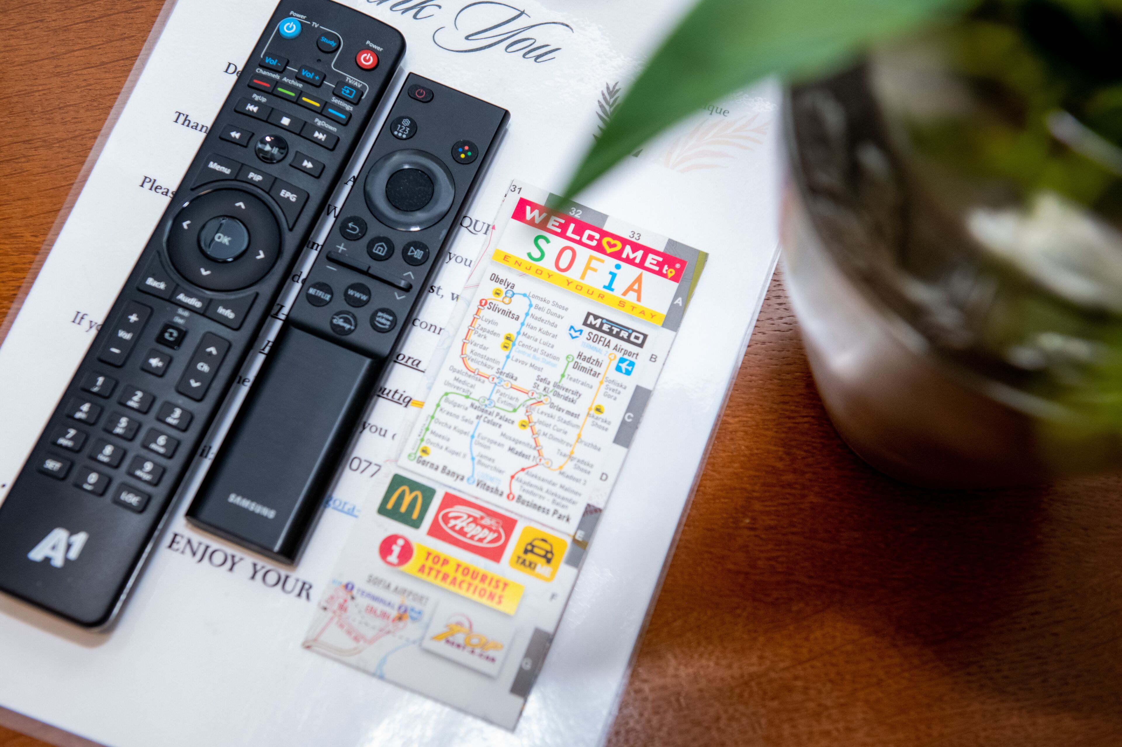 Two remote controls and a welcome brochure on a table.