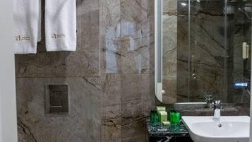 A modern bathroom with a marble wall, a toilet, a sink, and a mirror.