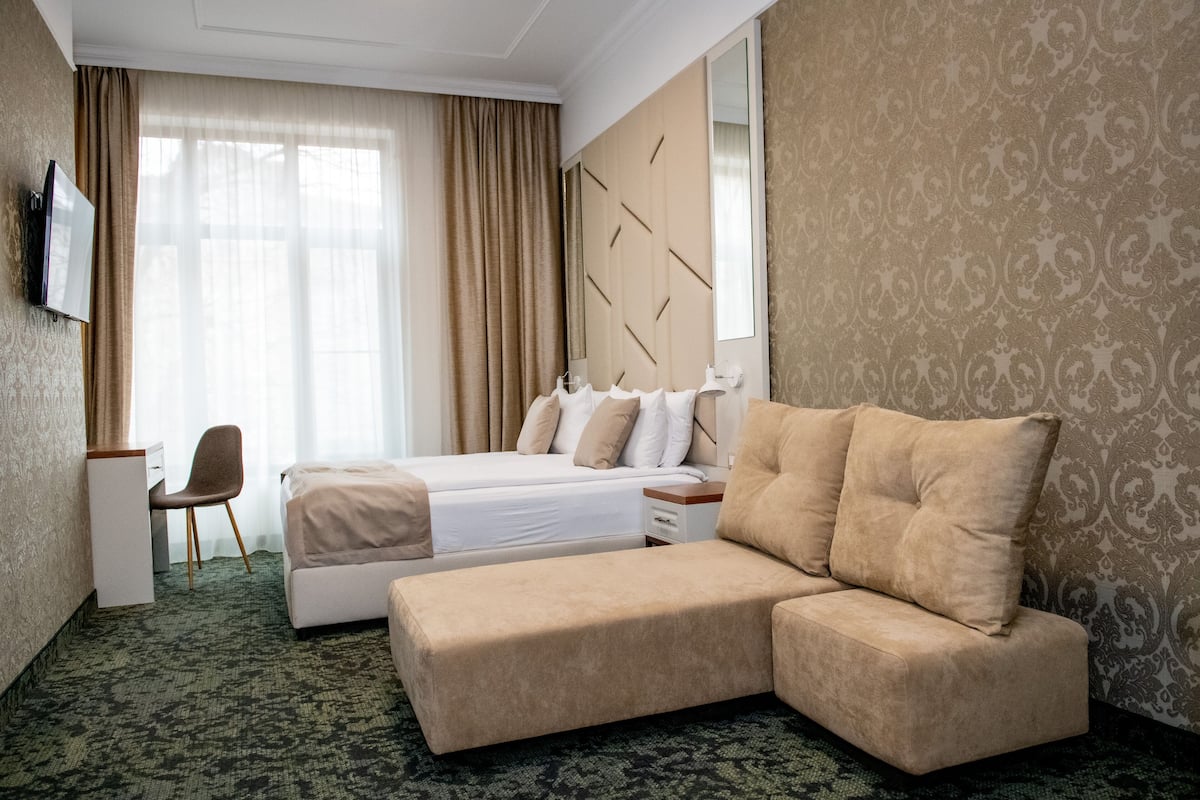 Quarto de hotel com cama, sofá, escrivaninha e cadeira.