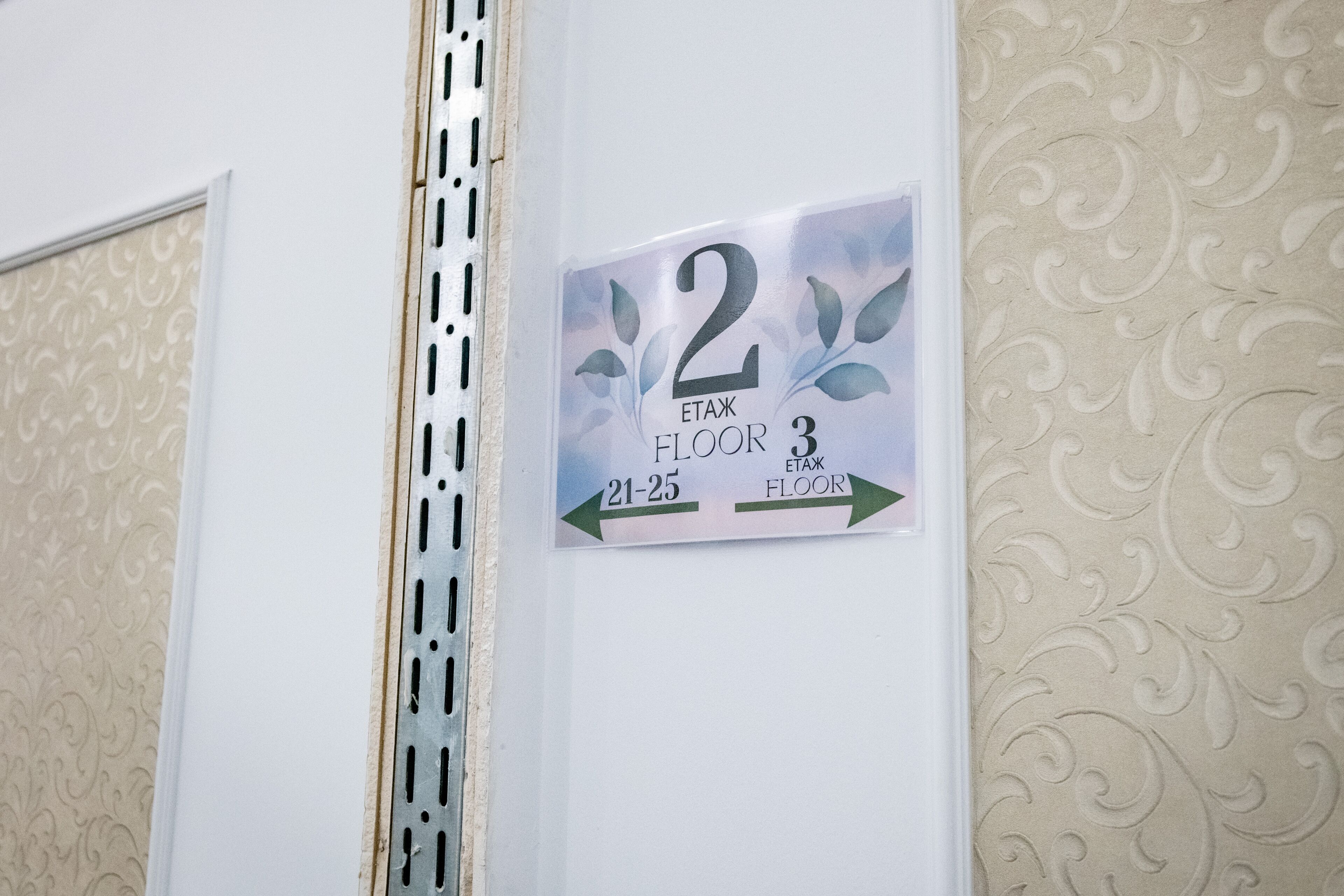 A wall sign indicating room number 2 on the 2nd floor, with arrows pointing to rooms 21-25 on the 3rd floor.