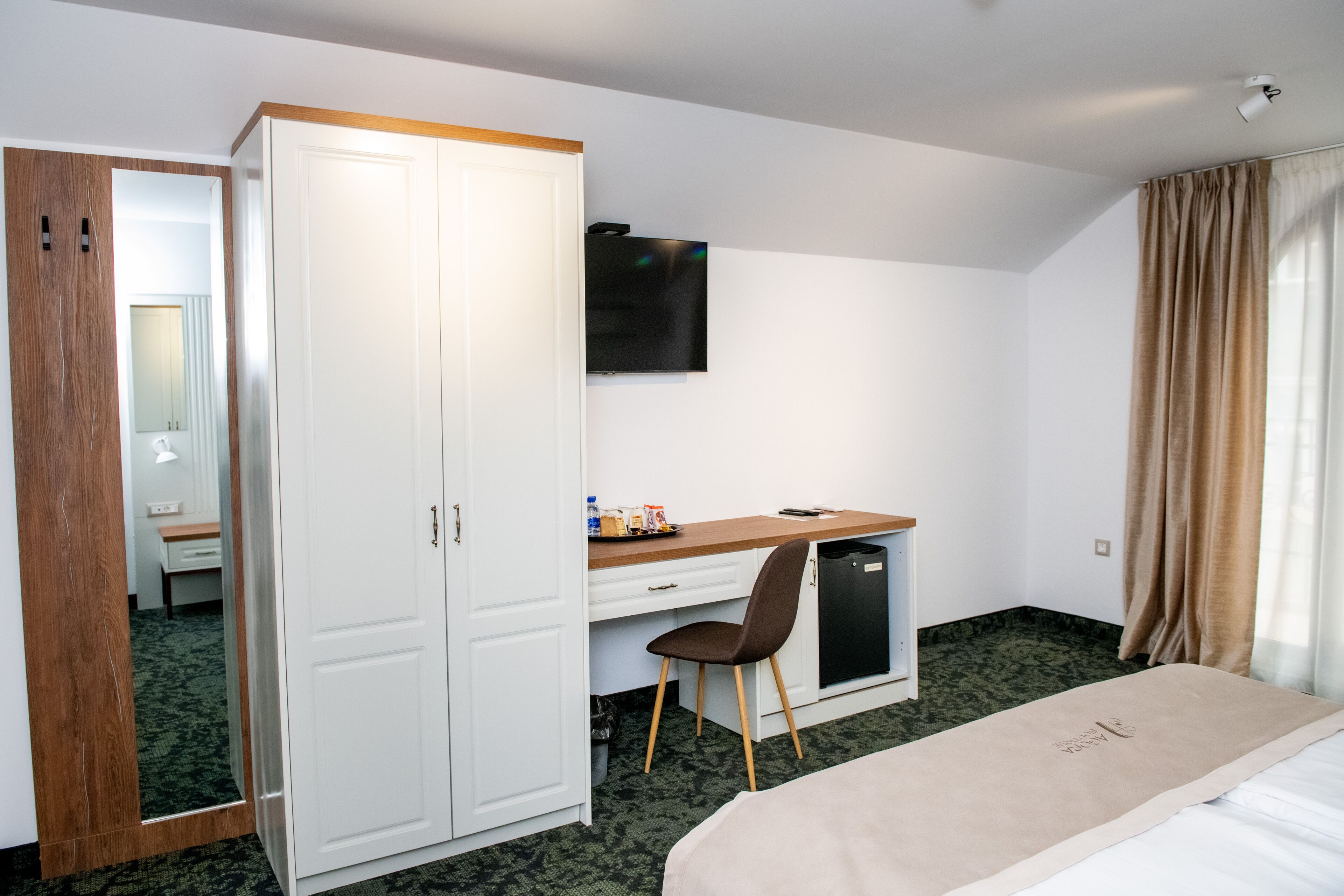 Ein Hotelzimmer mit Bett, Schreibtisch, Stuhl, Kleiderschrank, Fernseher und Badezimmer.