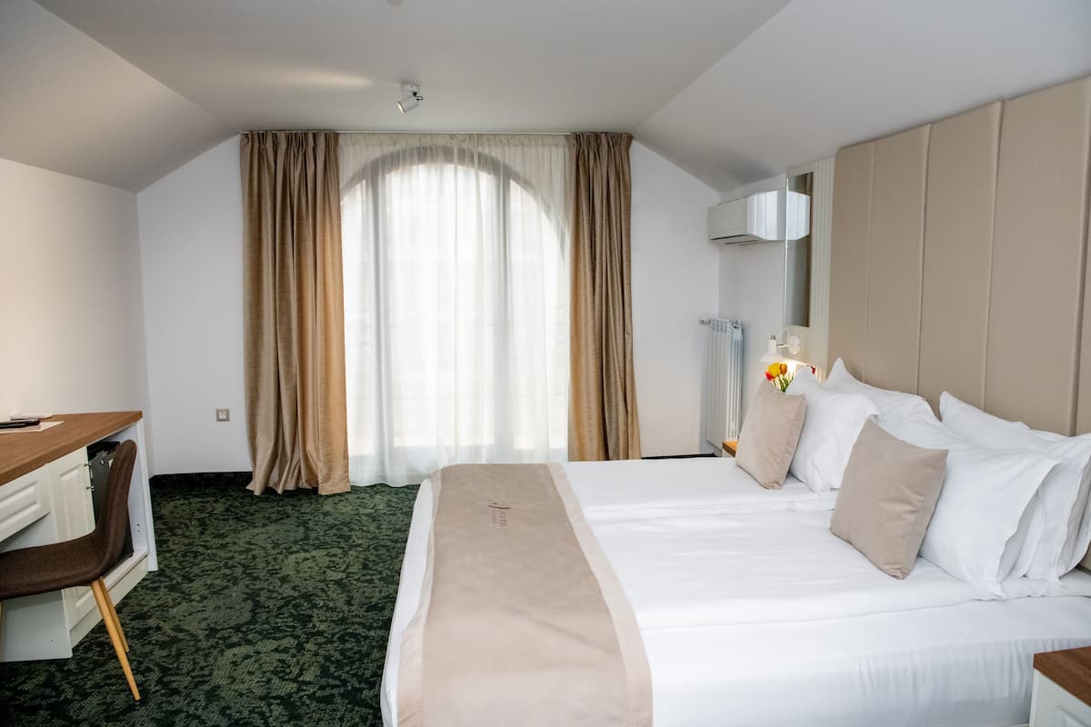 Quarto de hotel com uma cama, uma escrivaninha e uma cadeira.