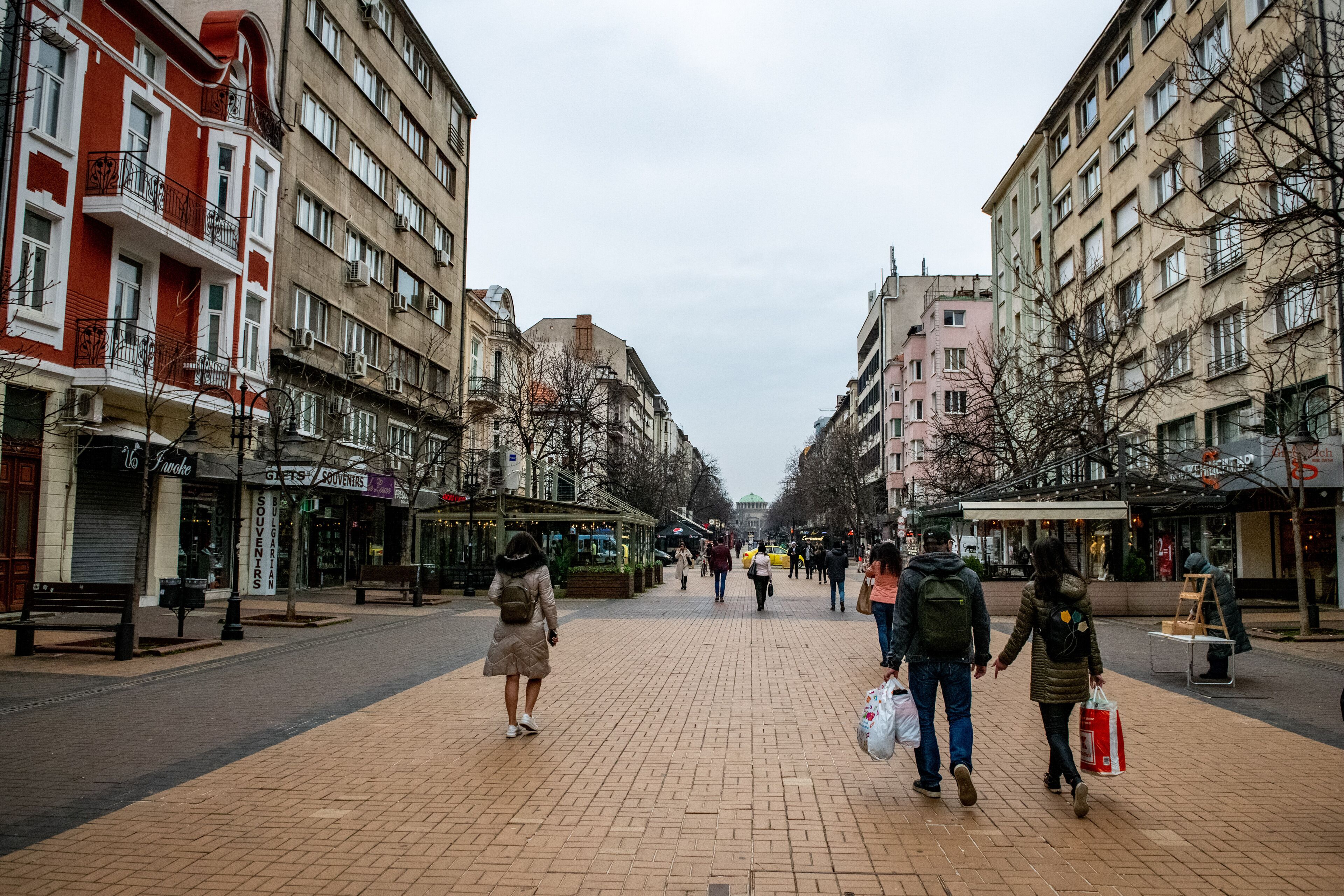 Uma rua para pedestres flanqueada por edifícios altos, alguns com varandas e aparelhos de ar condicionado.