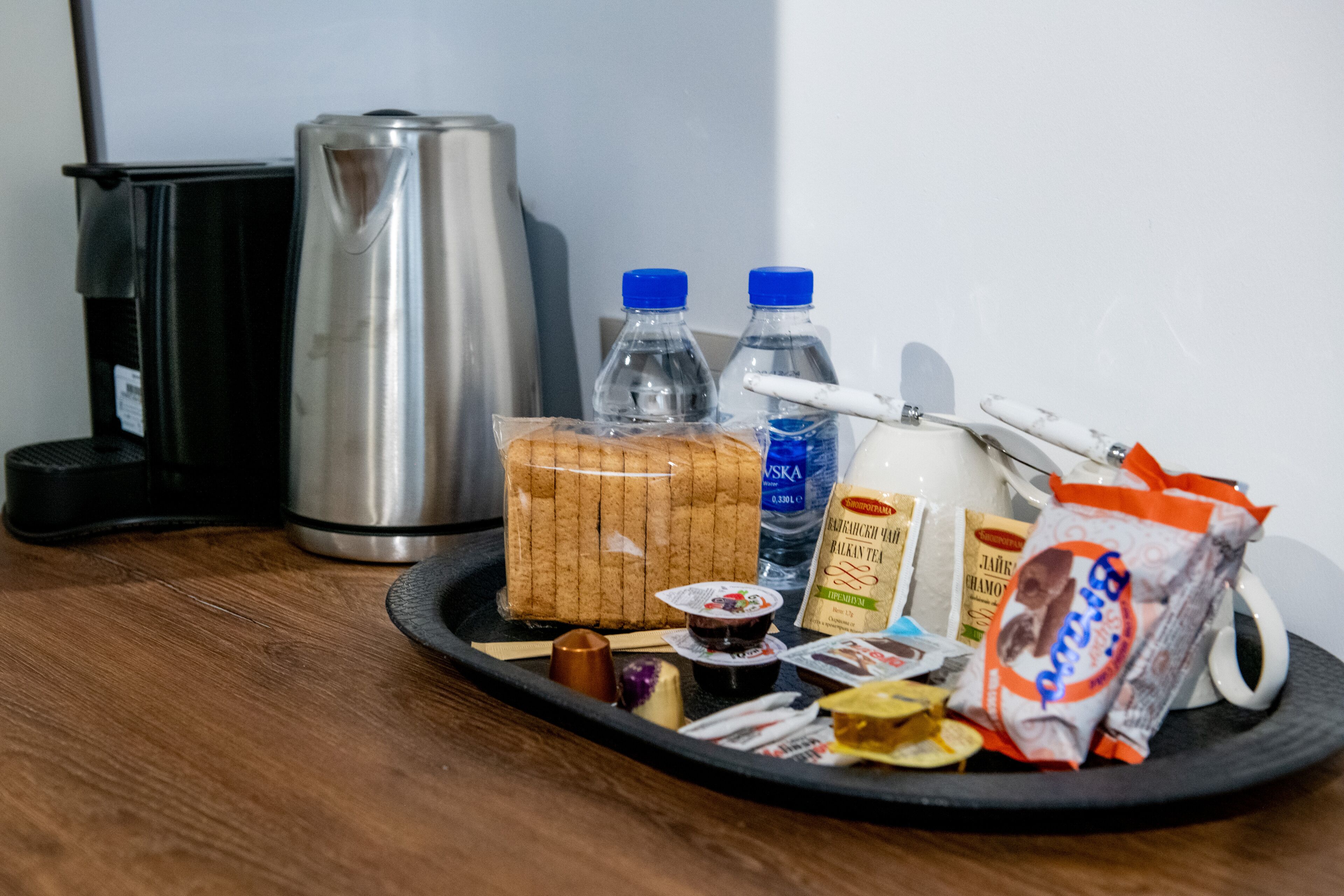 A tray with food items, a thermos, and bottled water on a wooden surface.