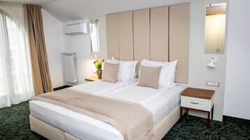 A hotel room with a large bed, a bedside table, a lamp, and a mirror.