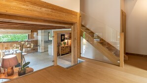 Ein modernes Interieur mit einer Holztreppe, einem Essbereich mit Tageslicht und Blick ins Freie.