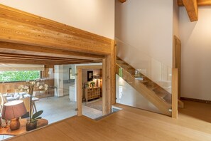 Ein modernes Interieur mit einer Holztreppe, einem Essbereich mit Tageslicht und Blick ins Freie.