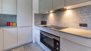 Eine moderne Küche mit weißen Schränken, einer Granitabdeckung und einem eingebauten Backofen.