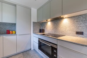 Eine moderne Küche mit weißen Schränken, einer Granitabdeckung und einem eingebauten Backofen.