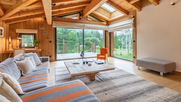 Ein geräumiges Wohnzimmer mit Holzboden, einer Couch, einem Couchtisch und einer Bank.