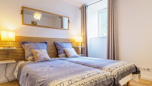 Quarto com uma cama grande, duas luminárias de cabeceira, um espelho e um lustre.