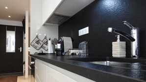 Uma cozinha moderna com bancada preta, pia de aço inoxidável e máquina de café.