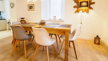 Un comedor con una mesa de madera, cuatro sillas, un adorno en la pared y una ventana con luz natural.
