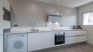 Una cocina moderna con electrodomésticos integrados, un amplio ventanal y luces empotradas en el techo.