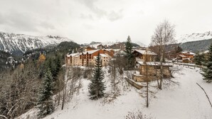 A snow-covered mountain resort with multiple wooden buildings, surrounded by trees and mountains. - SmartStay Grand Soleil - Courchevel 1650 (Courchevel)