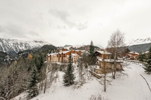 Ein schneebedecktes Bergresort mit mehreren Holzbauten, umgeben von Bäumen und Bergen.