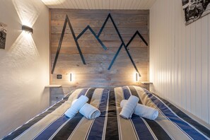 Ein Hotelzimmer mit Wandgestaltung aus Holz, einem Bett mit gestreifter Bettwäsche und zwei Nachttischlampen.