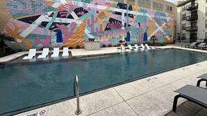 A swimming pool with a colorful mural, lounge chairs, and a poolside area. - Luxury Living Steps from The Domain: Austin's Premier Shopping Haven! (Austin)
