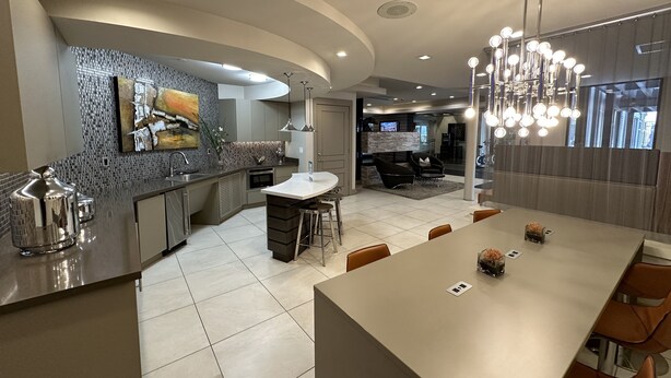 A modern kitchen with a curved island, built-in appliances, and a large dining area with bar stools. - Luxury Living Steps from The Domain: Austin's Premier Shopping Haven! (Austin)