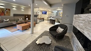A modern living room with a sofa, coffee table, and a fireplace. There is a kitchen area with a dining table and bar stools. - Luxury Living Steps from The Domain: Austin's Premier Shopping Haven! (Austin)