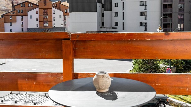 A terrace with a table and benches, overlooking a mountain range and modern buildings. - Smartstay Altineige - Val Thorens (Val-Thorens)