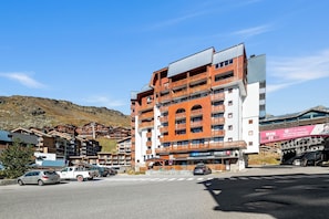 A multi-story hotel with balconies, a ski shop, and a view of the surrounding mountainous area. - Smartstay Altineige - Val Thorens (Val-Thorens)