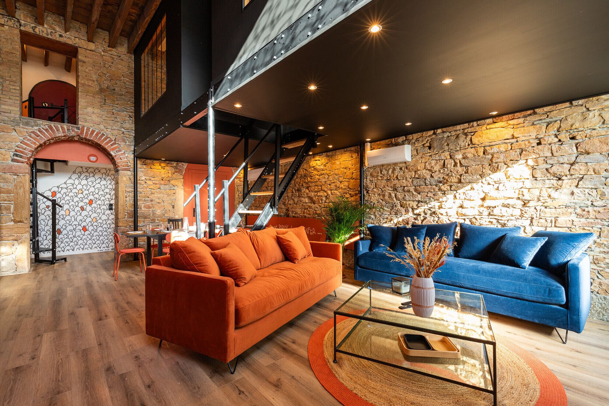 Un salon moderne avec un mur en pierre, un escalier et deux canapés.