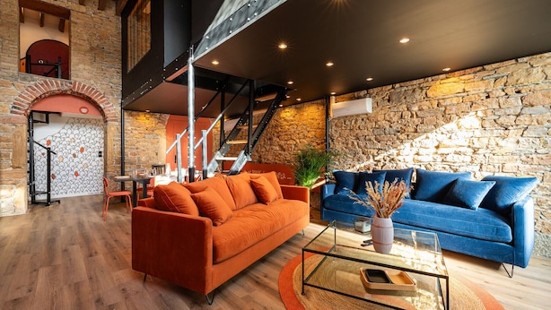 A modern living room with a stone wall, a staircase, and two sofas.
