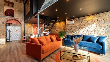 Un salon moderne avec un mur en pierre, un escalier et deux canapés.