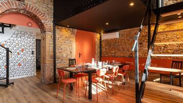 Un restaurant avec un mur en pierre rustique, un plancher en bois et des chaises rouges.