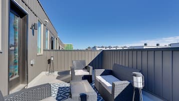 Relax on the rooftop with a city view, surrounded by a seating area and floor lamp.