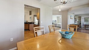 Un vaste espace dédié à la salle à manger, avec une table et des chaises en bois, un lustre et un panier rempli de balles.