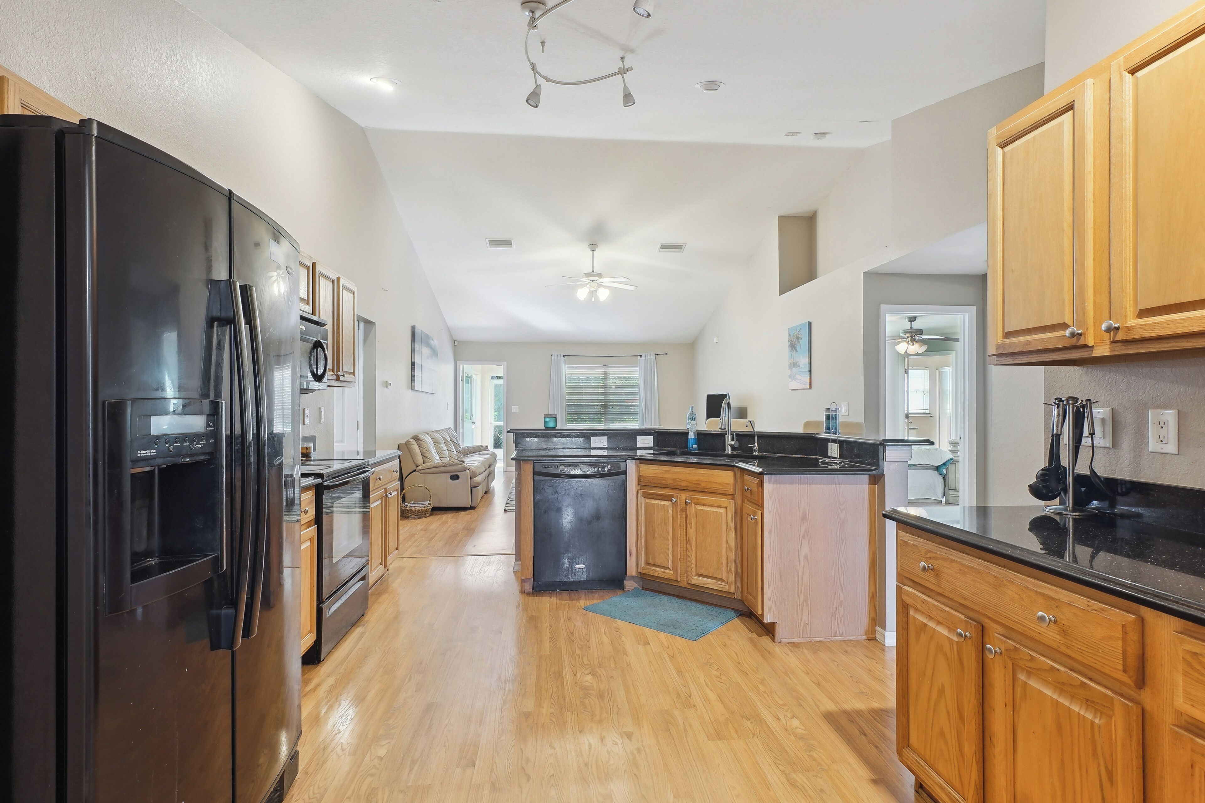 A spacious kitchen with a black refrigerator, wooden cabinets, and a central island.