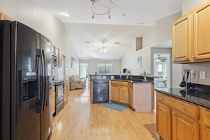 A spacious kitchen with a black refrigerator, wooden cabinets, and a central island. - Pet-friendly Home w/ Backyard in Cape Coral! (Cape Coral)