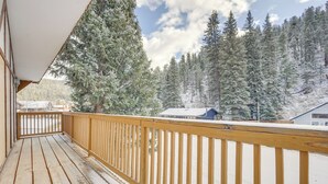 A wooden deck with a railing, overlooking a snowy forest and buildings. - Mountainside Bliss: Red River Getaway w/ Fireplace (Red River)