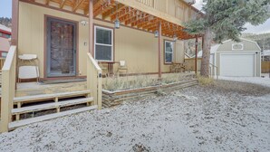 A two-story building with a wooden deck, a door, and a garage. - Mountainside Bliss: Red River Getaway w/ Fireplace (Red River)