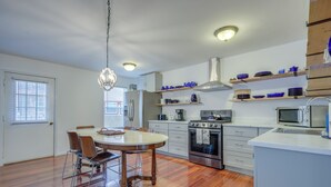 A modern kitchen with wooden flooring, a dining table with chairs, built-in appliances, and shelves with blue dishes. - Mountainside Bliss: Red River Getaway w/ Fireplace (Red River)