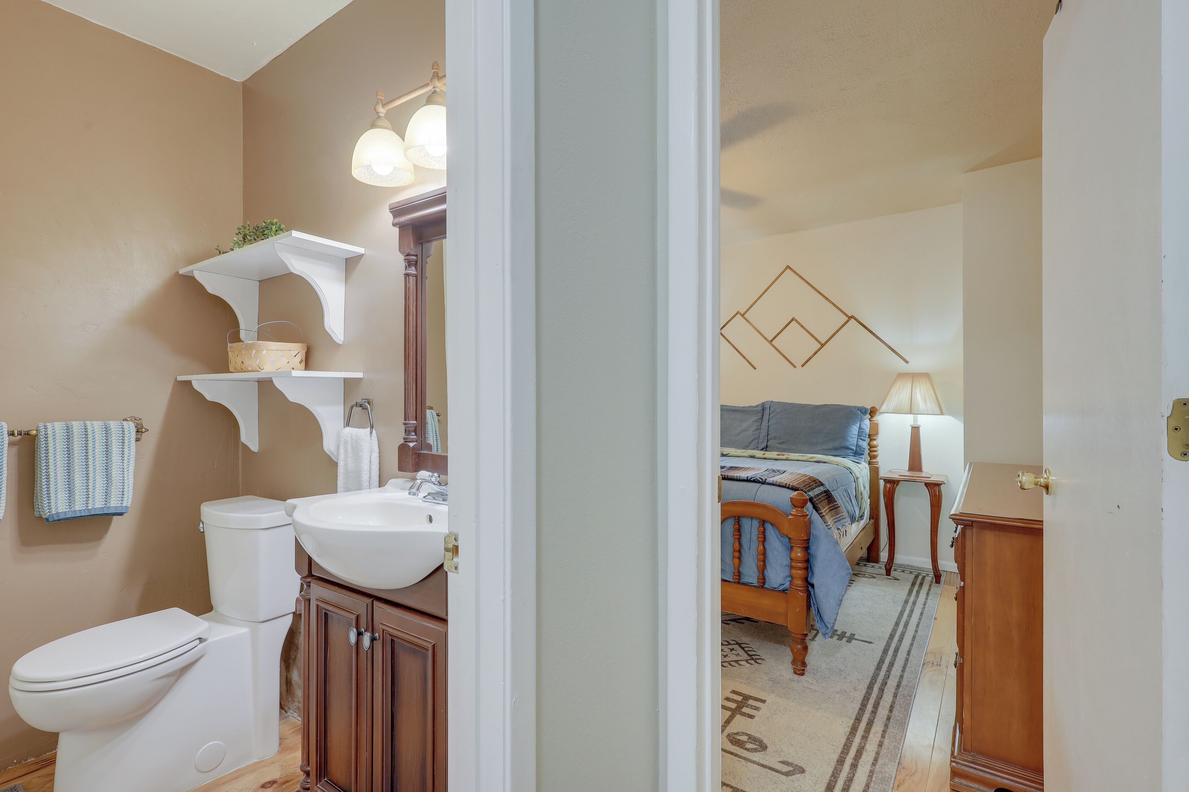 A bathroom with a toilet, sink, and wooden cabinets.
